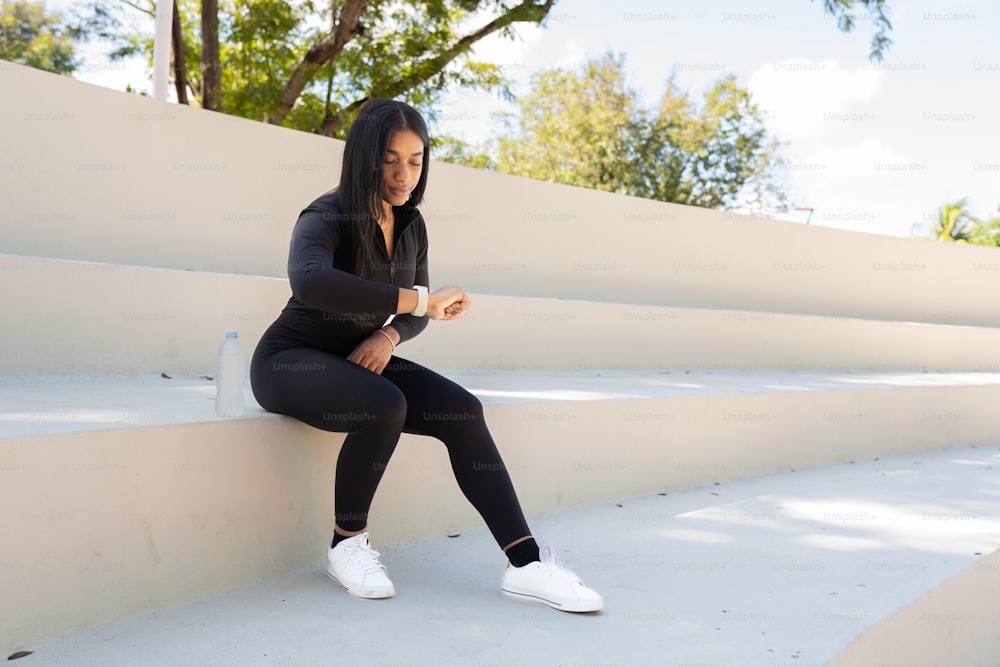 a woman is sitting on a wall and looking at her phone