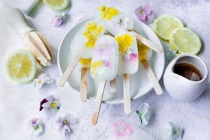 une assiette blanche surmontée de sucettes glacées recouvertes de fleurs