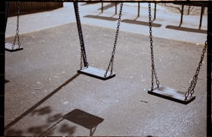 un parque infantil con columpios y la sombra de una persona en el suelo
