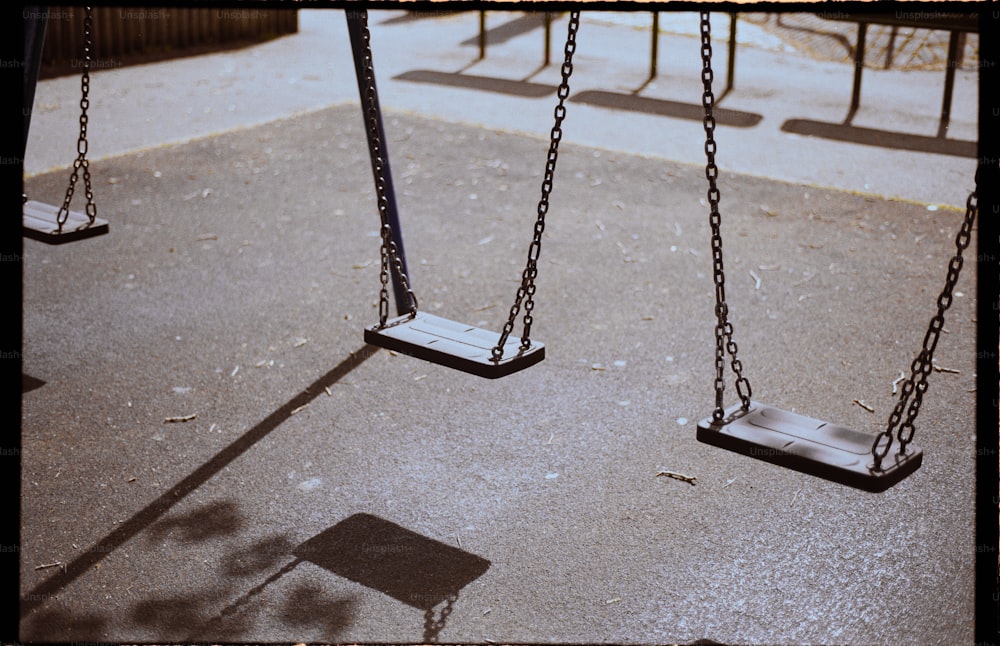 a playground with swings and a shadow of a person on the ground