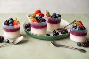 três sobremesas com frutas vermelhas e iogurte em um prato