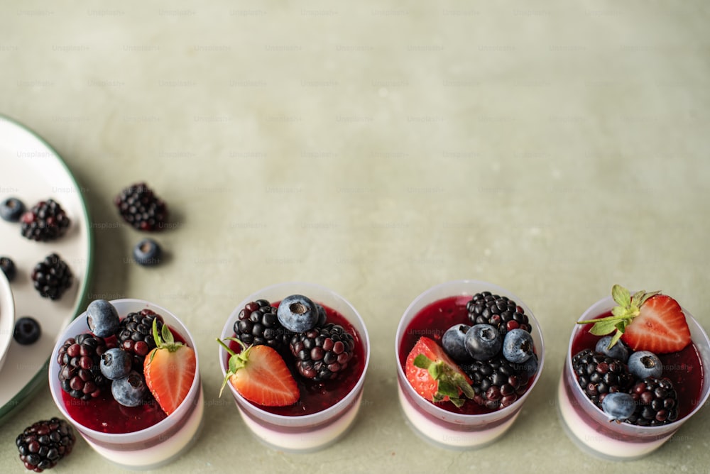 four small bowls of berries and blueberries on a table