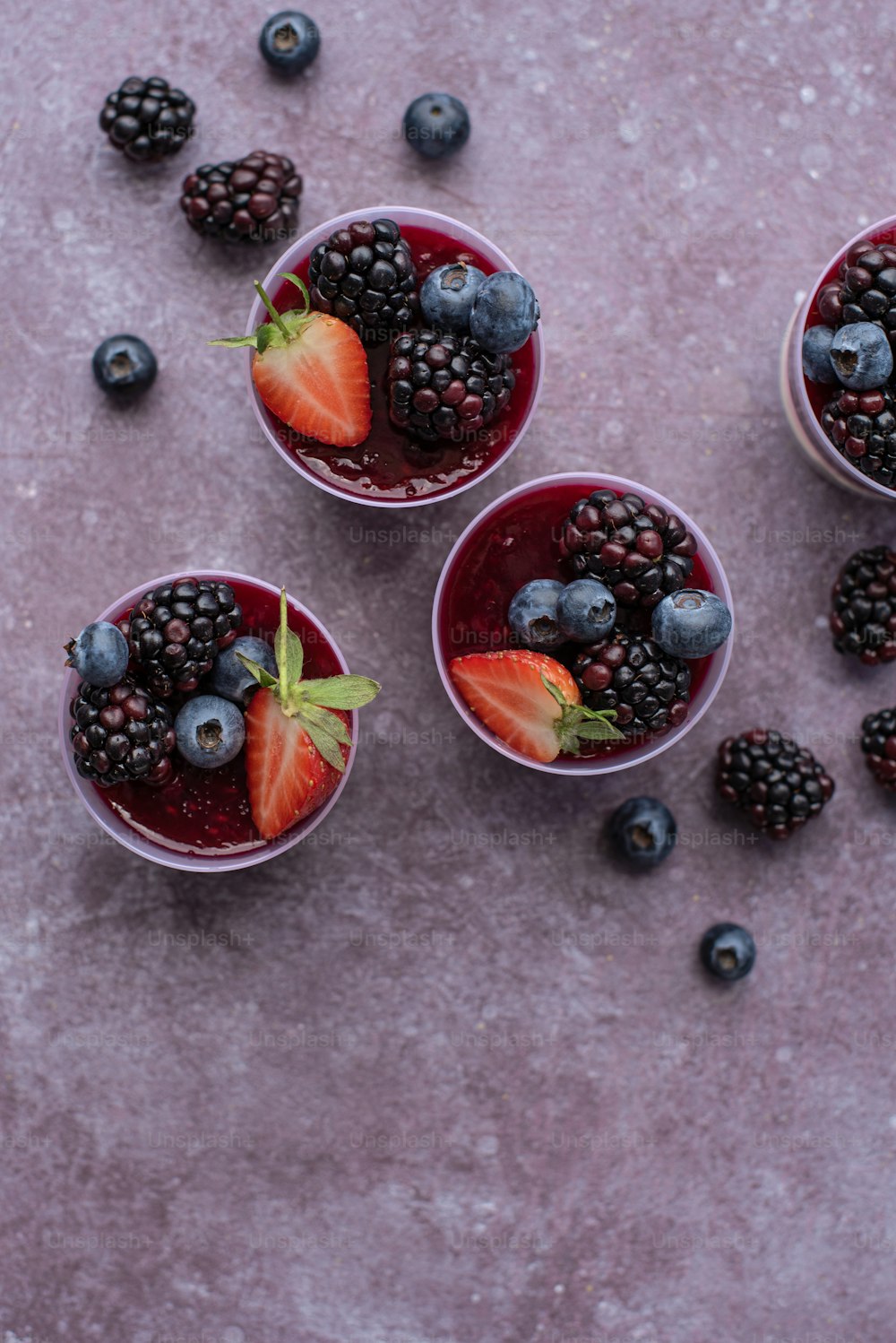three small cups filled with berries and blueberries