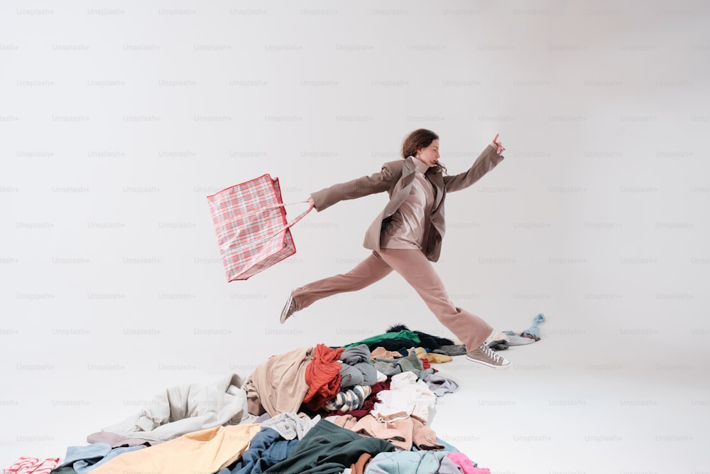 a woman jumping in the air over a pile of clothes