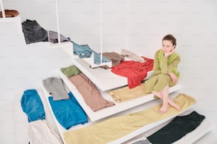 a woman sitting on a bench next to a pile of clothes