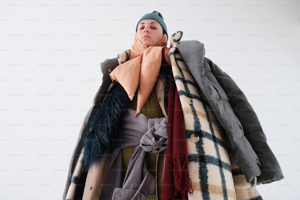 Una mujer sostiene una pila de abrigos