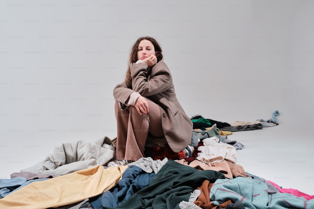 a woman sitting on a pile of clothes