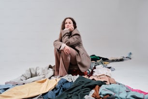 eine Frau, die auf einem Haufen Kleidung sitzt