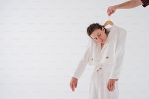 a woman in a white suit holding a wooden hanger