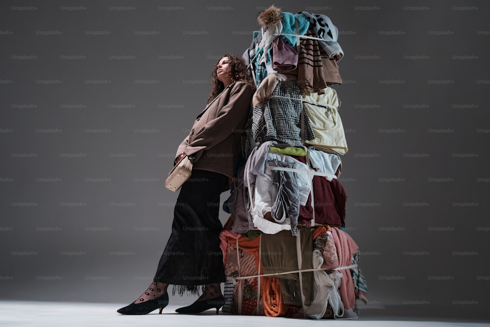 a woman standing next to a pile of clothes