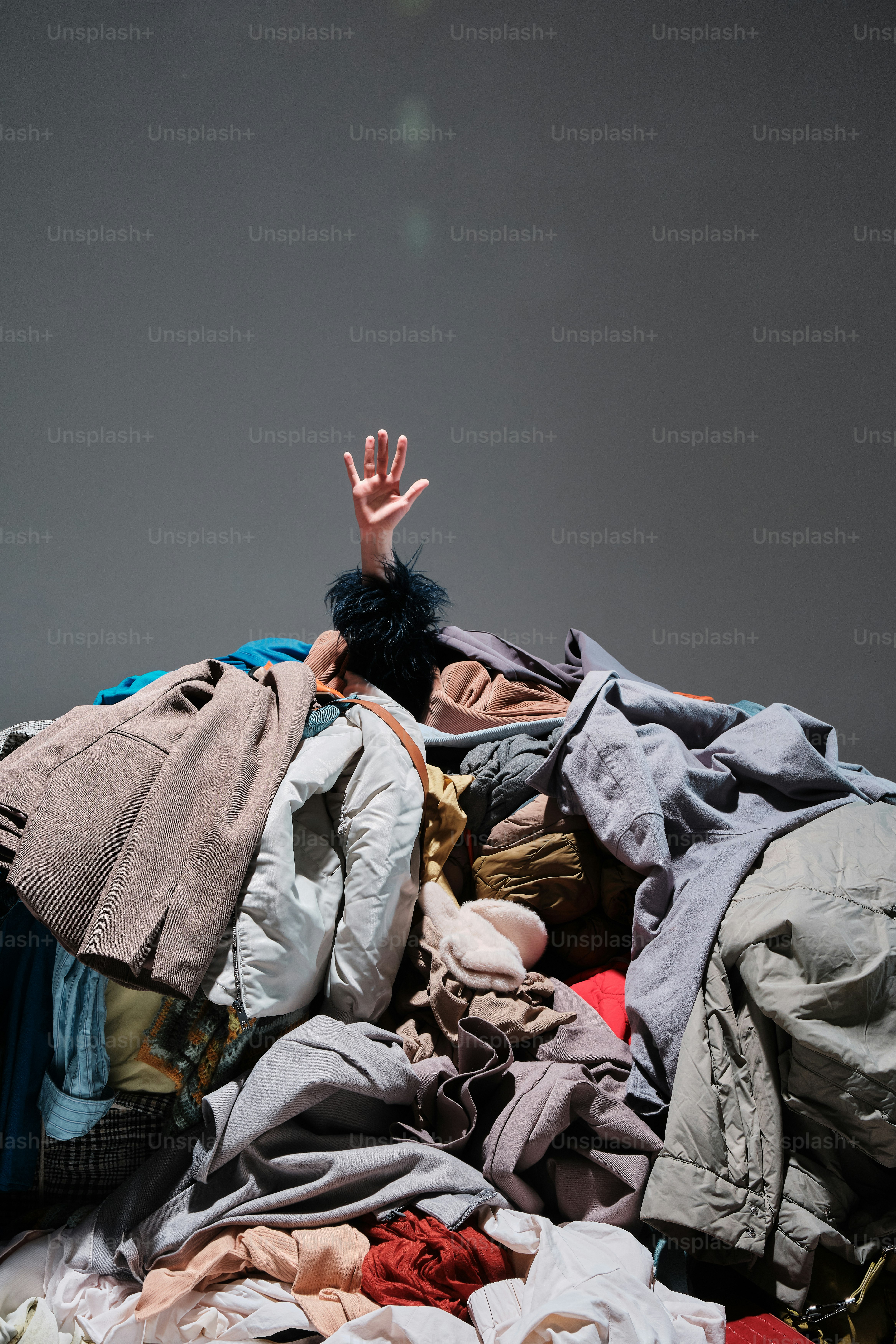 a pile of clothes with a person reaching up