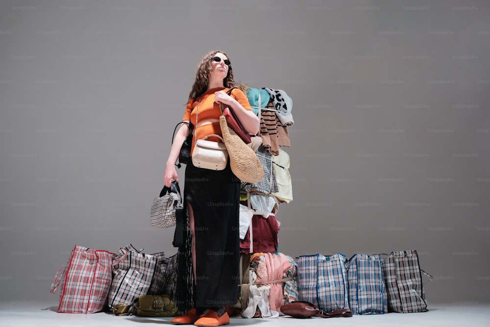 a woman standing in front of a pile of bags