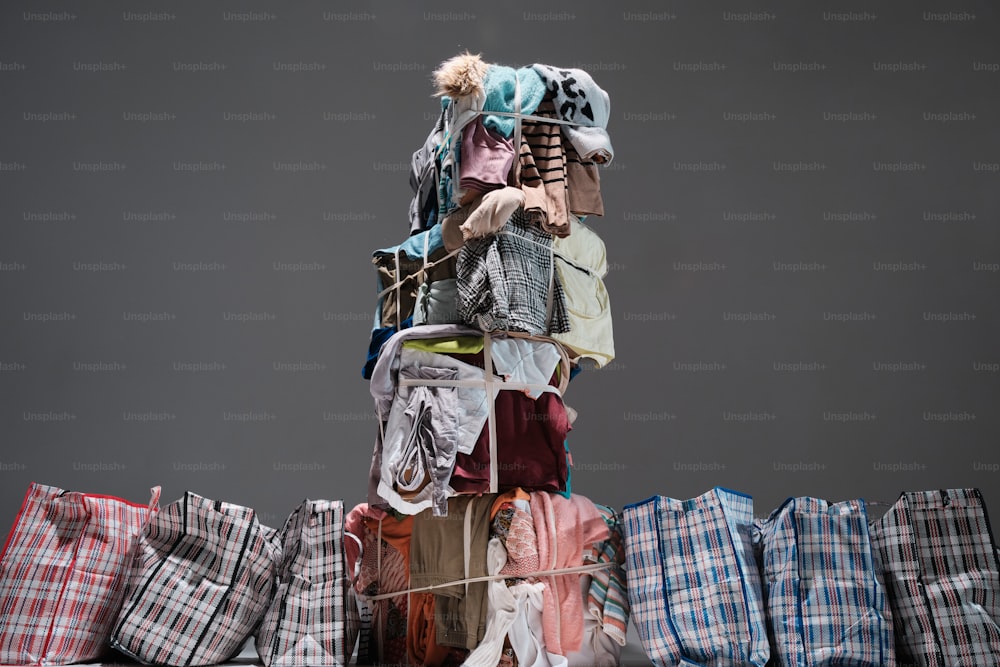 a pile of clothes sitting on top of a pile of bags