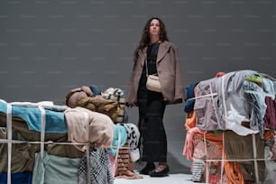 una donna in piedi davanti a una pila di vestiti