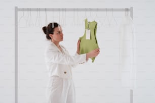 a woman in a white suit holding a green piece of clothing