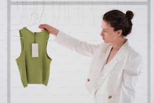 a woman looking at a green shirt hanging on a rack