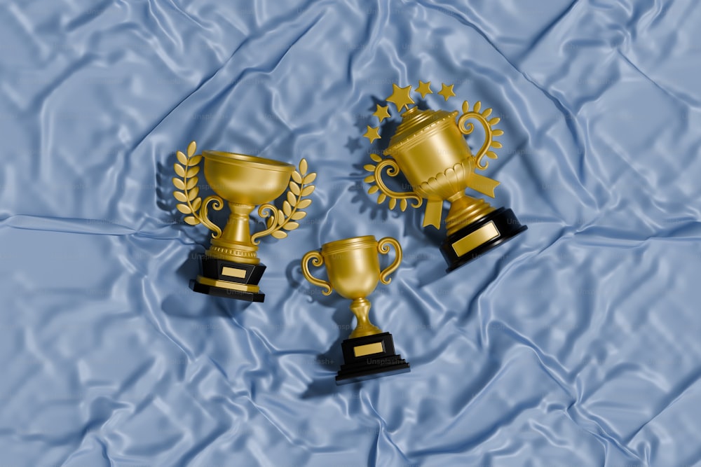 three golden trophies sitting on top of a blue sheet