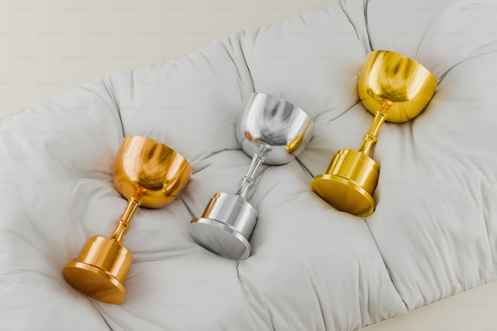 four gold and silver cups sitting on a cushion
