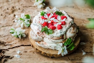 a cake with whipped cream and strawberries on a wooden board