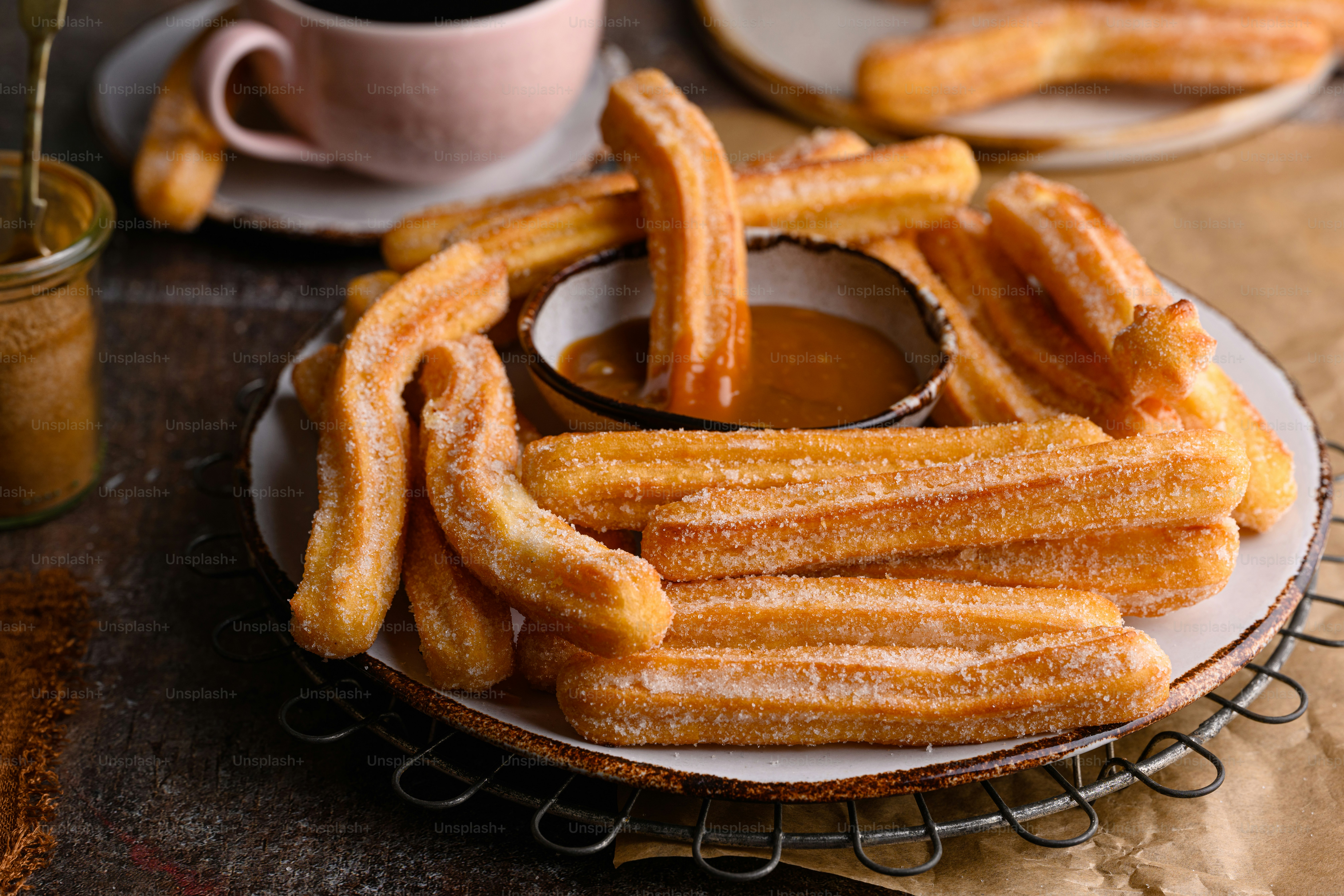 Un plato de churros sentado en una mesa junto a una taza de café
