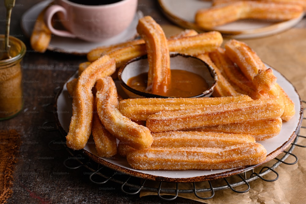 a plate of churros sitting on a table next to a cup of coffee