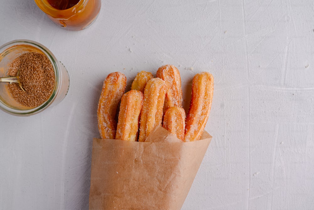 a paper bag filled with donuts next to a jar of mustard