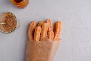 un sac en papier rempli de beignets à côté d’un pot de moutarde