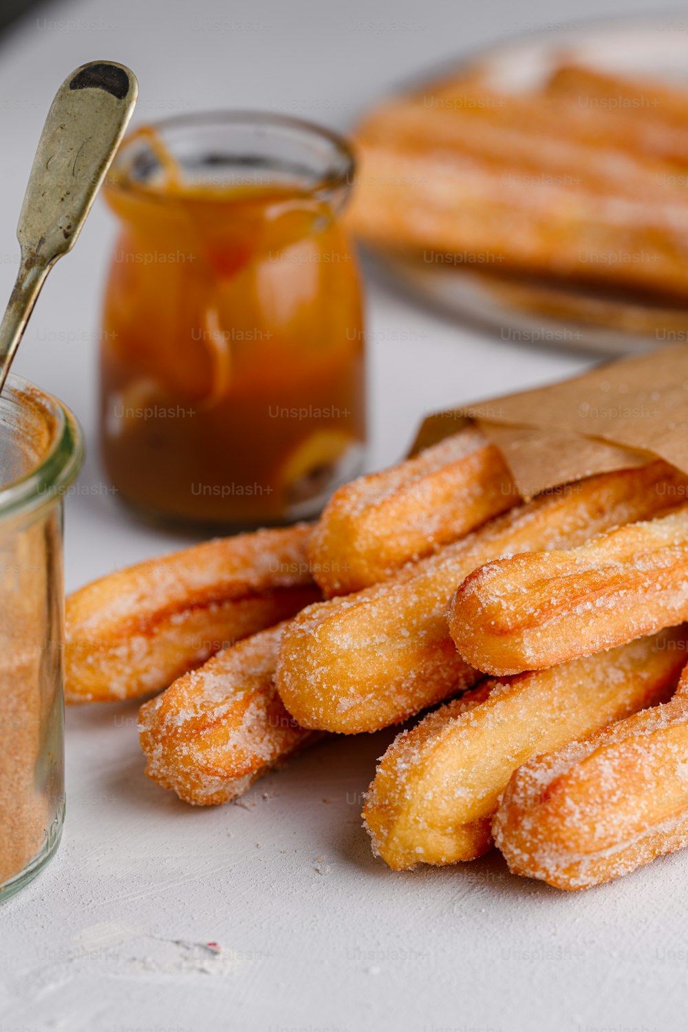 a pile of sugared donuts next to a jar of honey
