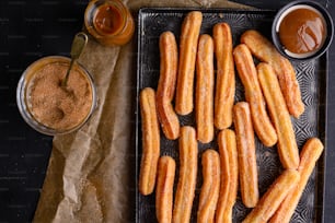 a tray of churros next to a cup of sauce