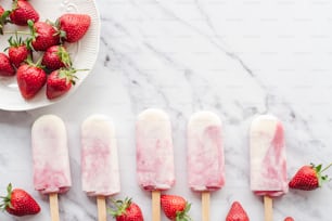 a marble table topped with popsicles and strawberries