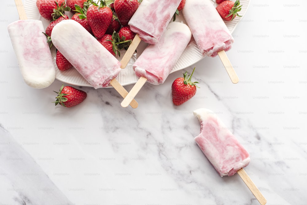 a plate of strawberries and popsicles on a marble table