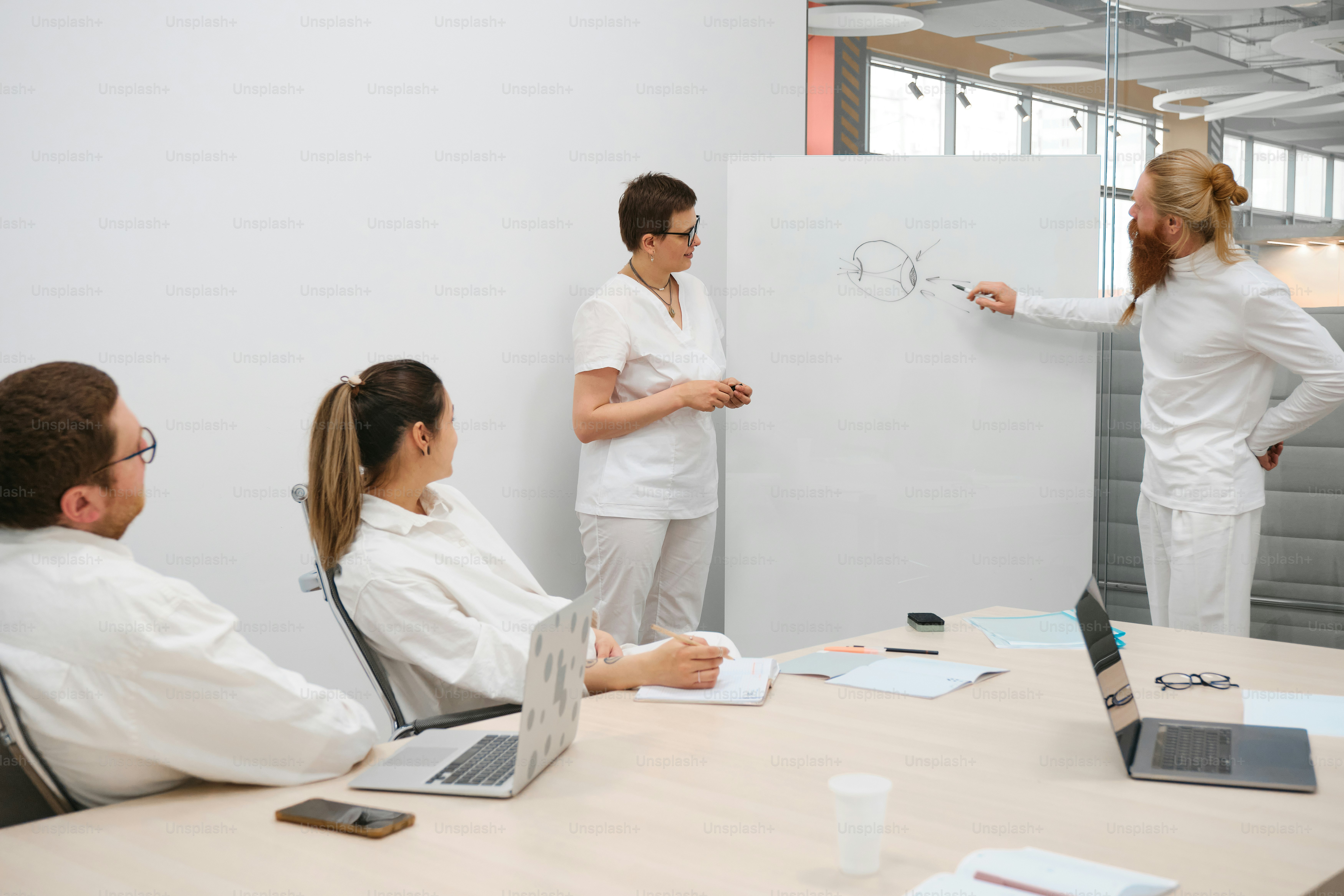 a group of people sitting around a table in front of a whiteboard