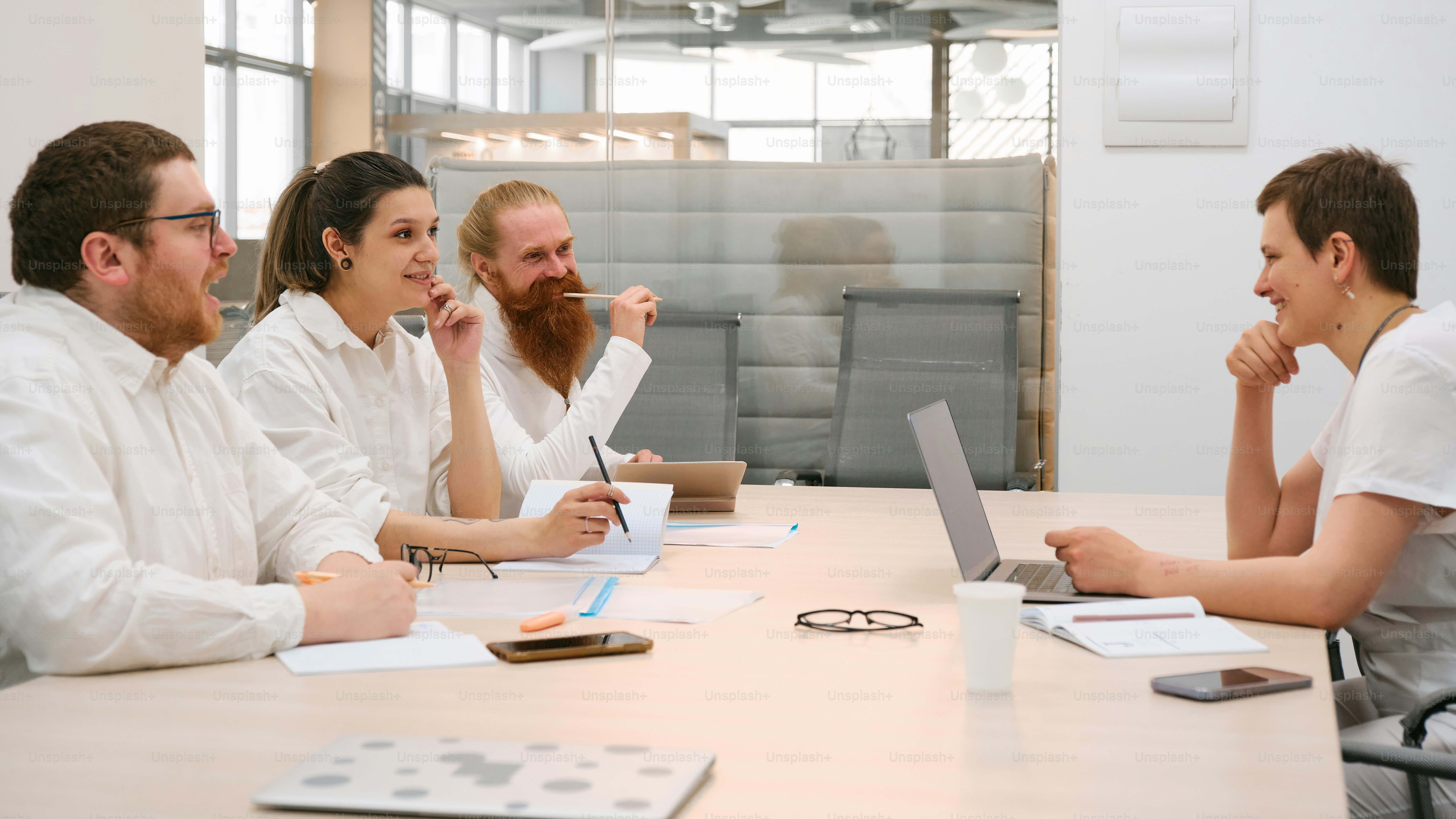 a group of people sitting around a table with laptops