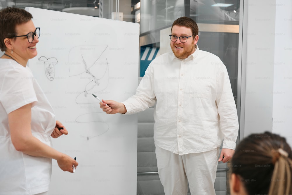 a man standing next to a woman in front of a whiteboard