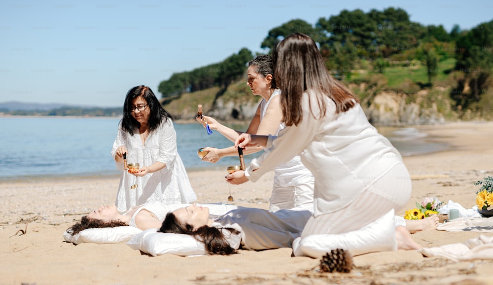 a group of women sitting on top of a sandy beach