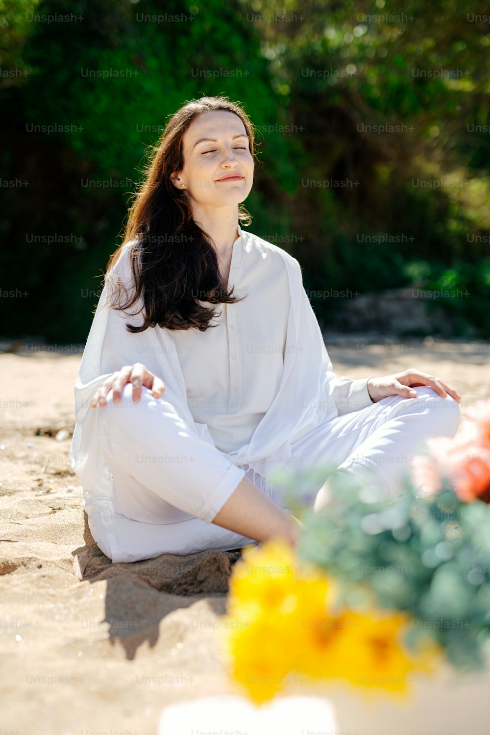 a woman sitting in the sand with her eyes closed