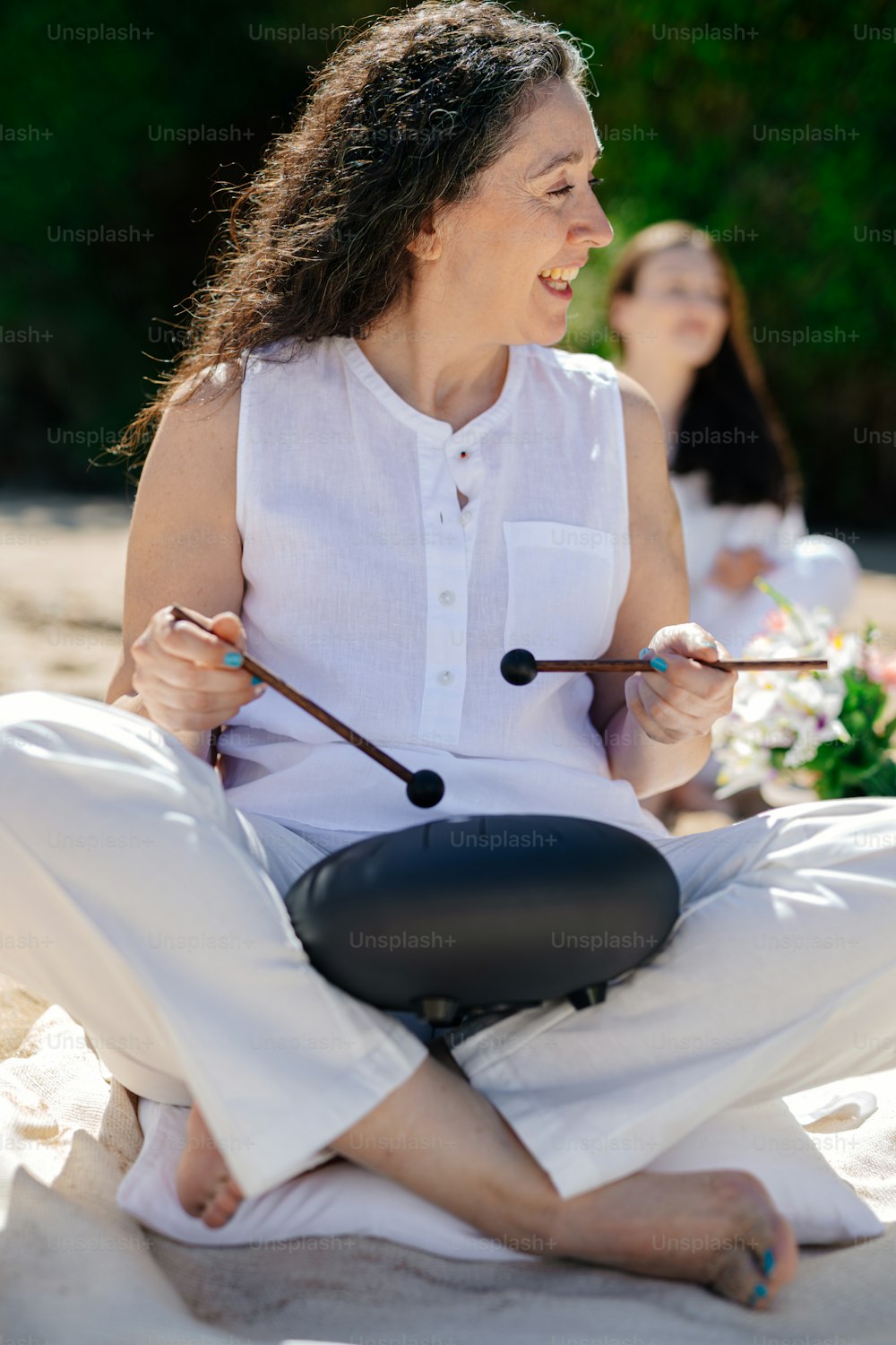 una mujer sentada en la arena con un palo en la mano
