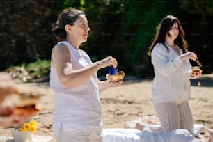 a couple of women sitting on top of a sandy beach