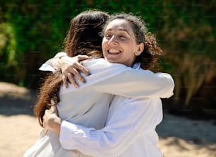 two women hugging each other on a sunny day