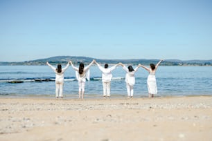 a group of women standing on top of a sandy beach