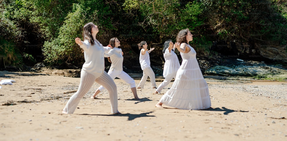 un grupo de mujeres con vestidos blancos bailando en una playa