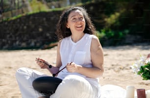 a woman sitting in the sand holding a guitar