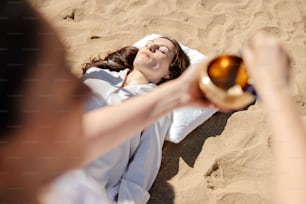 a woman laying in the sand holding a golden object