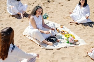 a group of women sitting on top of a sandy beach