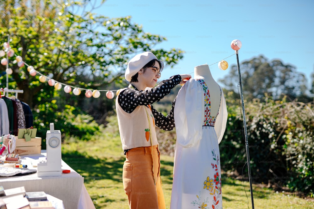 a woman standing next to a table with a dress on it