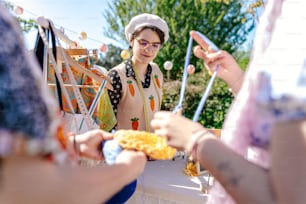 a group of people standing around a table with food