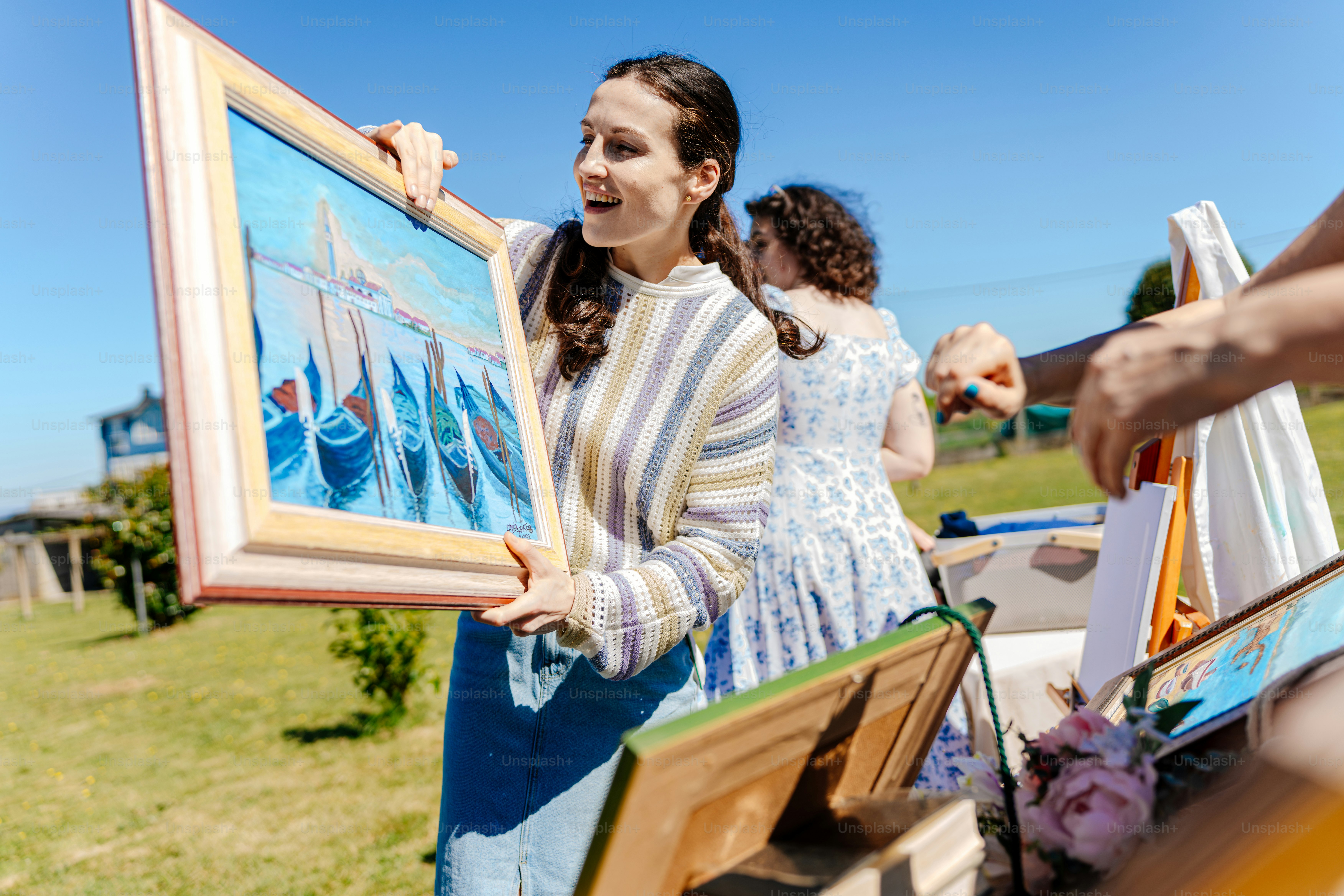 a woman holding up a painting in a field