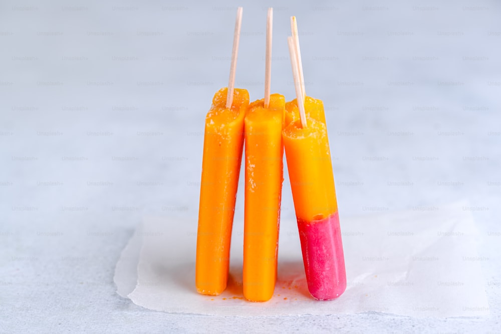 a group of orange and pink toothpicks sitting on top of a piece of