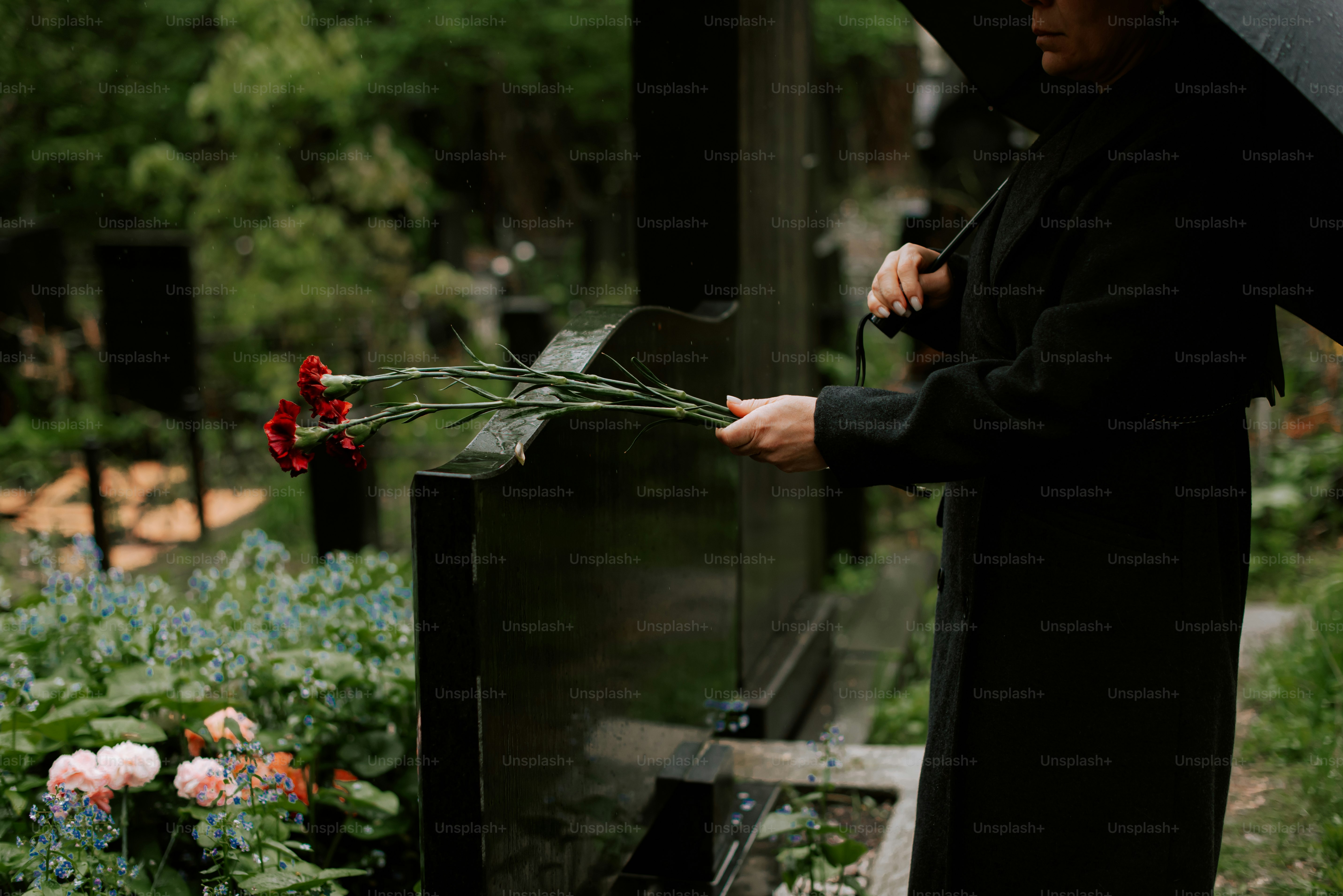 a woman holding an umbrella over a bunch of flowers