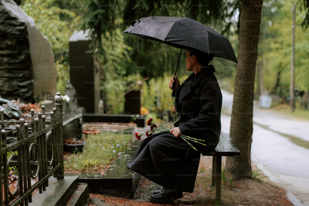 uma mulher sentada em um banco segurando um guarda-chuva
